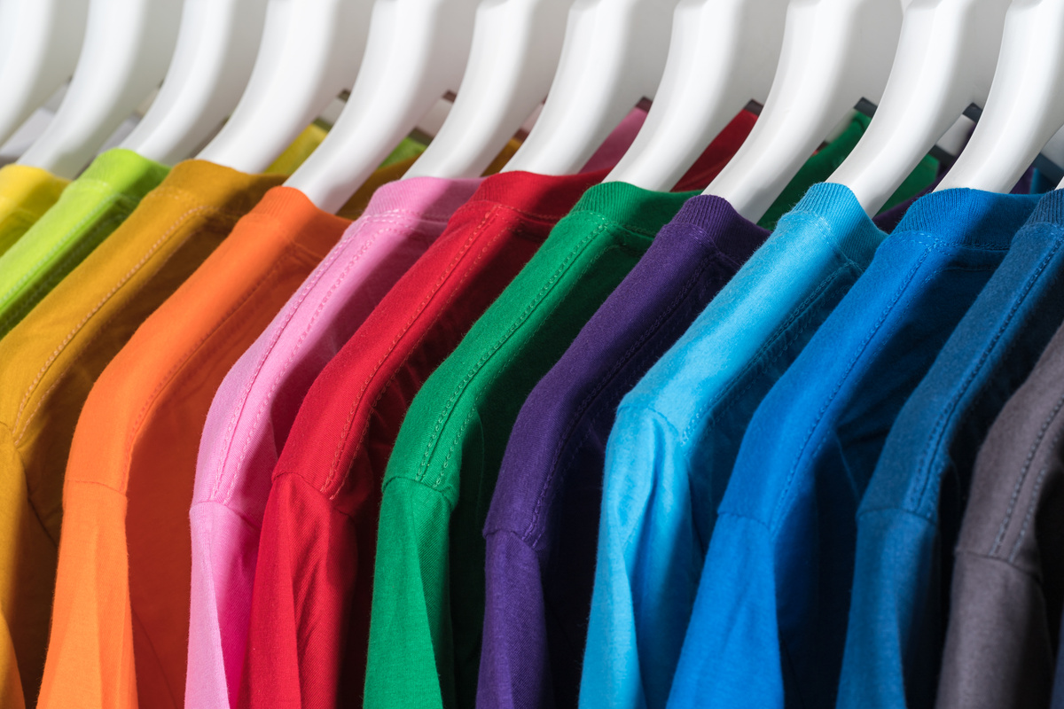 Hangers with colorful cotton t shirts in wardrobe